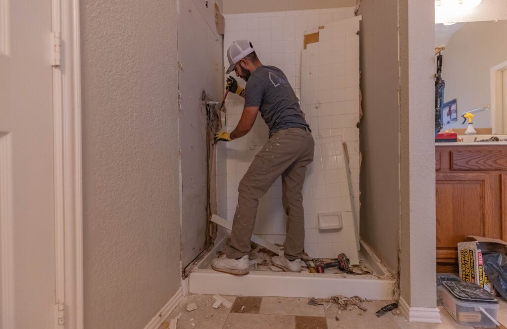 A shower installer works on the structure of a shower stall