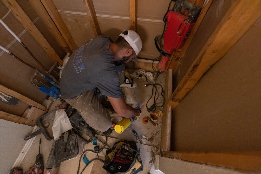 Photo of a ZINTEX technician working on the plumbing and floor of a shower wet area before installing the shower base