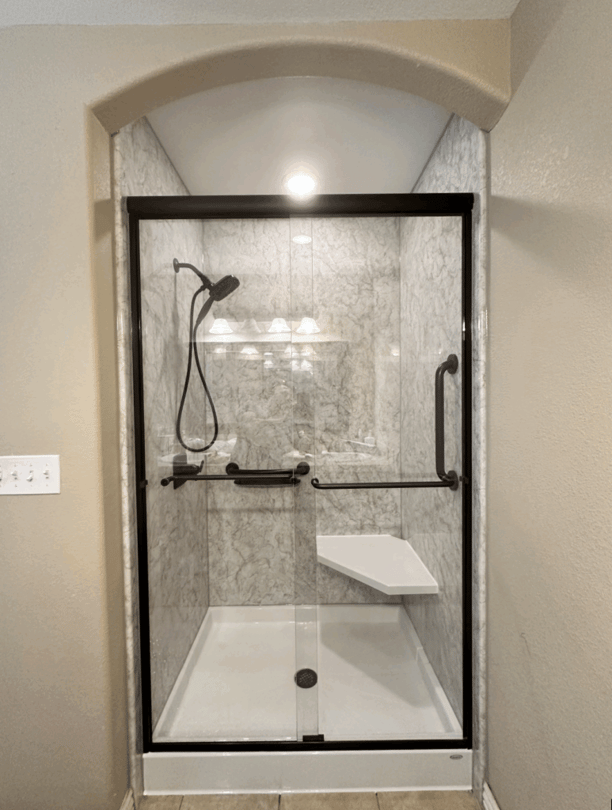 Photo of a stall walk in shower with a glass enclosure, corner seat, and detachable showerhead. This walk in shower maximizes space in a small bathroom.