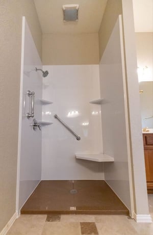 A basic walk in shower with a grab bar and seat