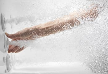 Photo of a hand reaching through water to adjust the hydro jet in a bathtub