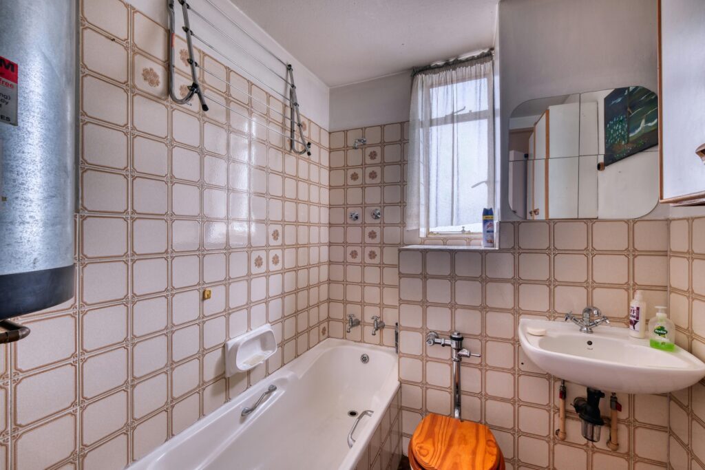Warm and inviting bathroom with beige tiles, featuring a bathtub and washbasin under bright natural light.
