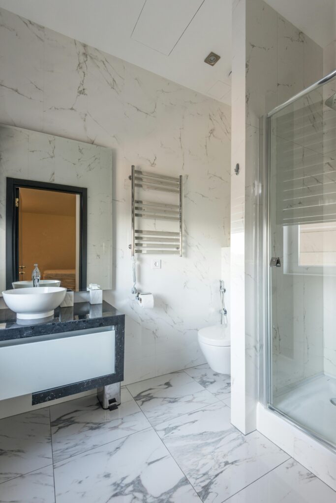 Modern bathroom with marble surfaces, sleek fixtures, and natural light.