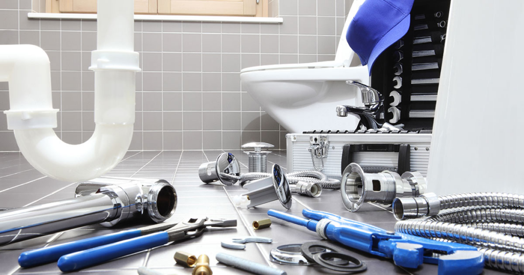 Concept photo of a toilet and the p-trap of a sink surrounded by plumbing tools